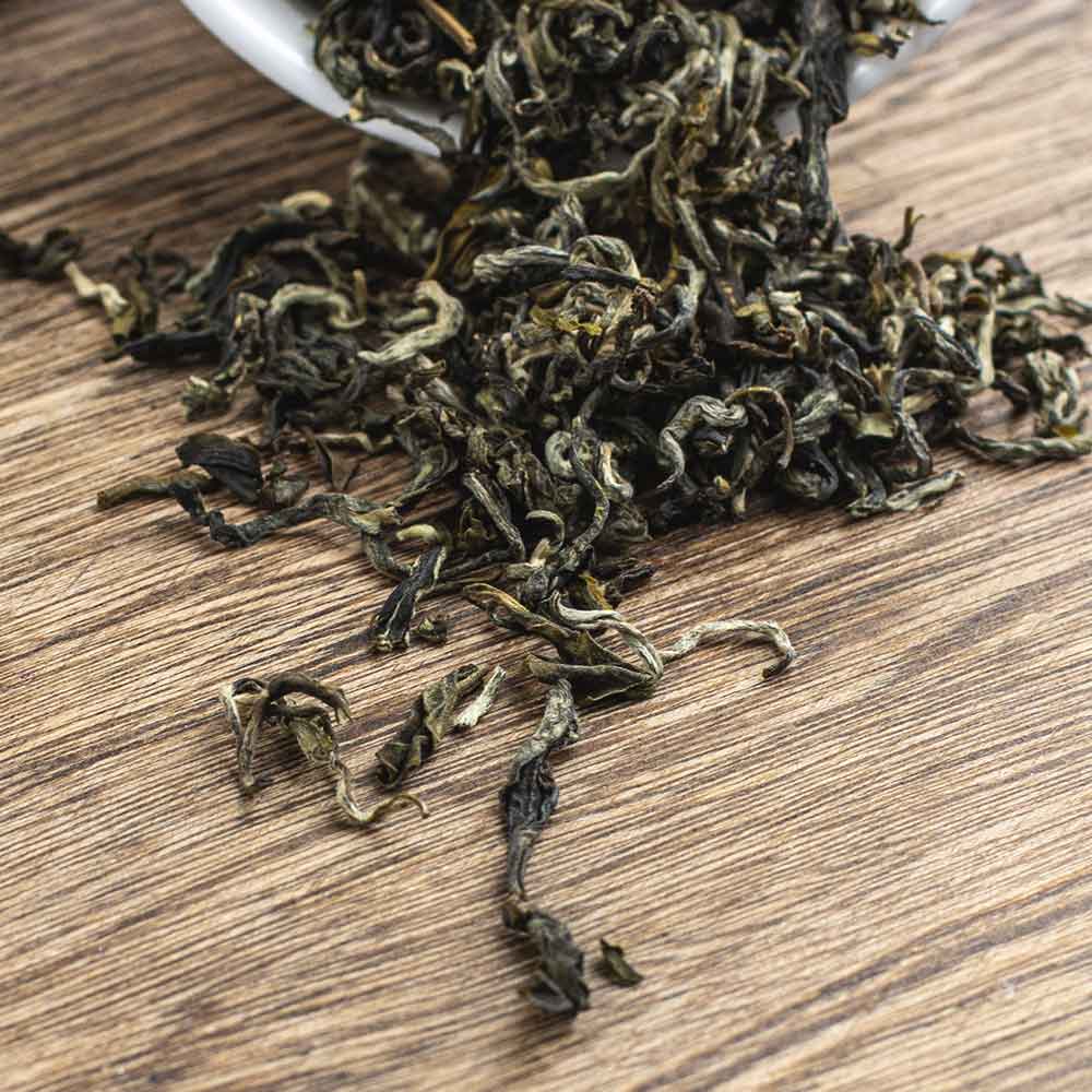 image of the individual leaves of our chinese whole leaf green tea on a wooden table.